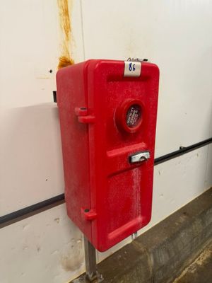 une borne d'incendie rouge adossée à un mur