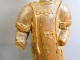 une statue en bois représentant un homme coiffé d'un chapeau