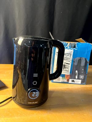 une cafetière noire posée sur une table à côté d'un ordinateur portable