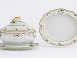 une assiette blanche ornée d'un oiseau, à côté d'un bol et d'une soucoupe