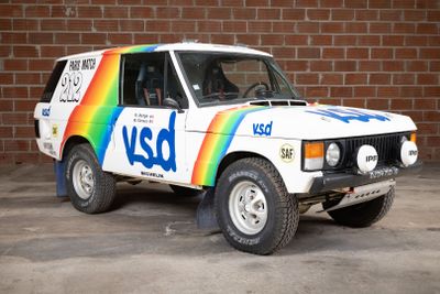 a white van with a rainbow painted on it parked in front of a brick wall