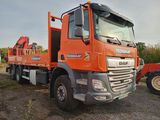 un gros camion orange garé sur la terre battue