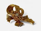 une image représentant une broche de couleur dorée ornée d'un nœud