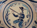 a blue and white plate with a picture of a man holding a rifle