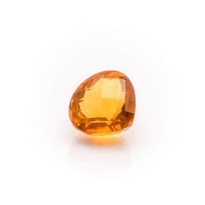 a close up of an orange sapphire stone on a white surface