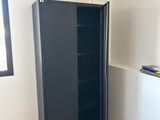 a black cabinet in the corner of a room next to a window