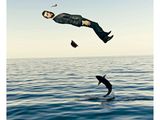 un homme en costume qui sort de l'eau d'un bond pour attraper un poisson