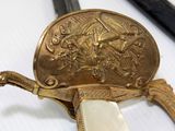 a close up of a gold plated sword with a white blade