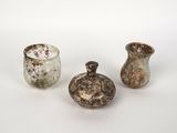 trois petits vases sont posés sur une surface blanche, devant un fond blanc