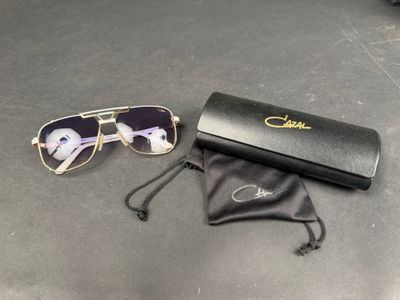 des lunettes de soleil et un étui noir posés sur une table, à côté d'une paire de lunettes
