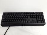 a black keyboard on a white surface with a black cord