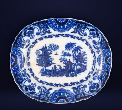 une assiette bleue et blanche sur laquelle est représenté un paysage