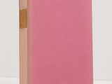 a pink book sitting on top of a table next to a white wall