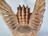 a wooden sculpture of a bird with wings on it ' s head
