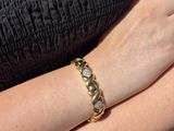 the woman is wearing a black dress and a gold bracelet