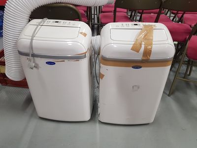 pair of white portable air conditioners sitting in a room with red chairs