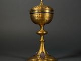 a gold cup with a cross on top of it