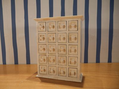 une petite commode en bois posée sur une table en bois
