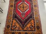 a red and orange rug sitting on top of a white floor