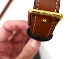 a person holding a brown and black watch in their hand