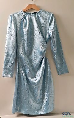 blue dress hanging on a hanger against a wall