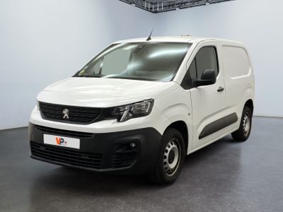 La camionnette blanche est garée dans une grande pièce au sol noir.