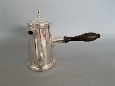 une cafetière en argent avec un manche en bois sur une table