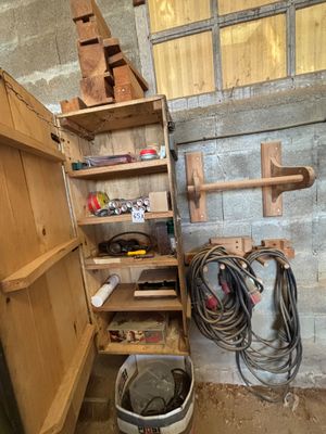 une étagère en bois sur laquelle sont posés des outils, dans un coin de la pièce