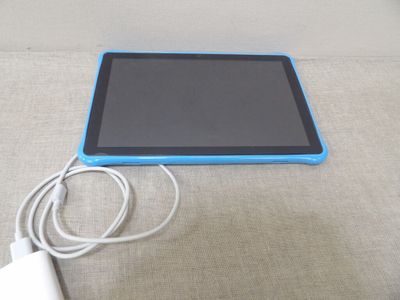 une tablette bleue posée sur une table à côté d'un chargeur