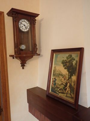 une photo d'une horloge accrochée au mur à côté d'un tableau