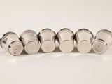 six silver salt shakers lined up in a row on a white surface