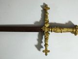 une épée dorée ornée d'une croix, sur un fond blanc