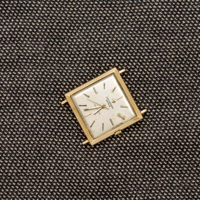 une image représentant une petite horloge carrée posée sur un morceau de tissu