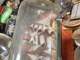 a glass bottle with a ship in it sitting inside of a box