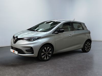 une voiture argentée garée dans une pièce blanche au sol noir