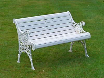 un banc blanc au milieu d'un champ herbeux