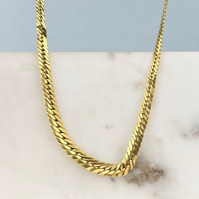 un gros plan d'un collier en or posé sur une surface en marbre