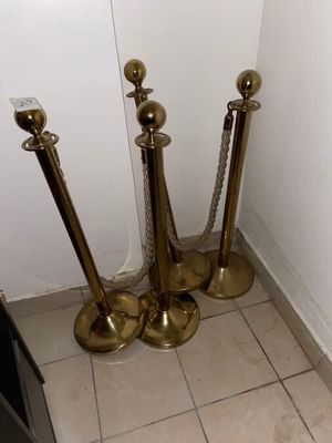 four brass candles that are on the floor next to a wall