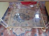 a glass coffee table with gold legs and a glass top