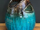 a blue and brown vase sitting on a wooden table