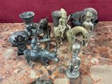 de nombreuses statues posées sur une table, avec un mur rouge en arrière-plan