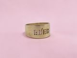 a close up of a gold ring on a pink background