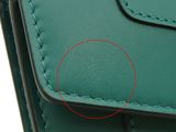 a close up of a green leather wallet with a red circle in the middle