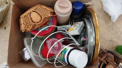 une boîte en carton remplie d'objets divers, posée par terre