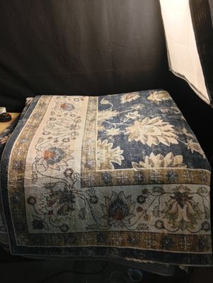 a small ottoman with a blanket on it in the corner of a room