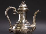 une théière ancienne en argent avec une anse en forme d'oiseau, sur fond noir