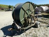 a large green hose on a cart in the dirt