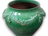 un vase vert orné d'une anse en forme de dragon sur fond blanc
