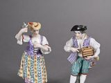 three porcelain figurines of people with musical instruments on a gray surface