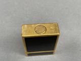 a close up of a gold and black ring on a gray surface